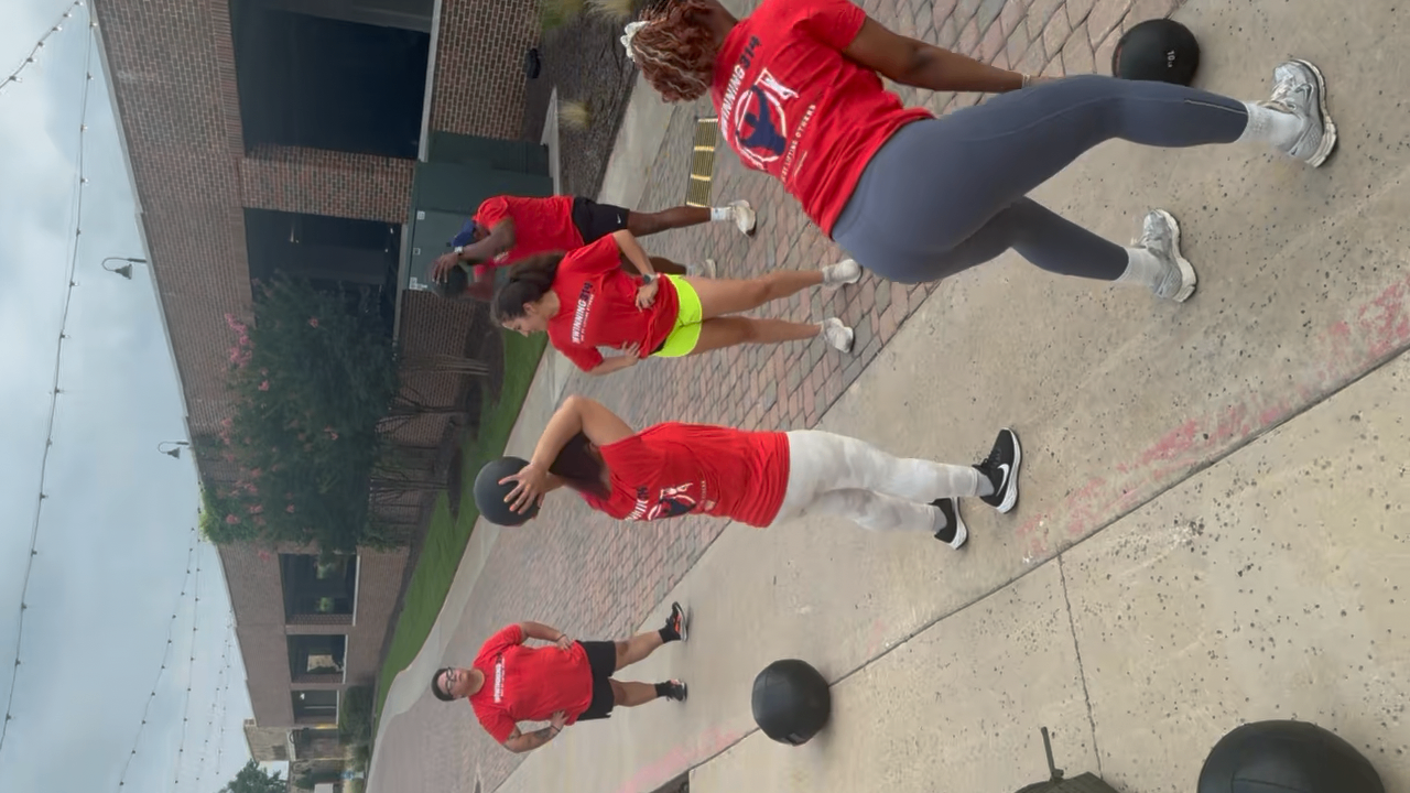 Members performing a medicine ball circuit outside